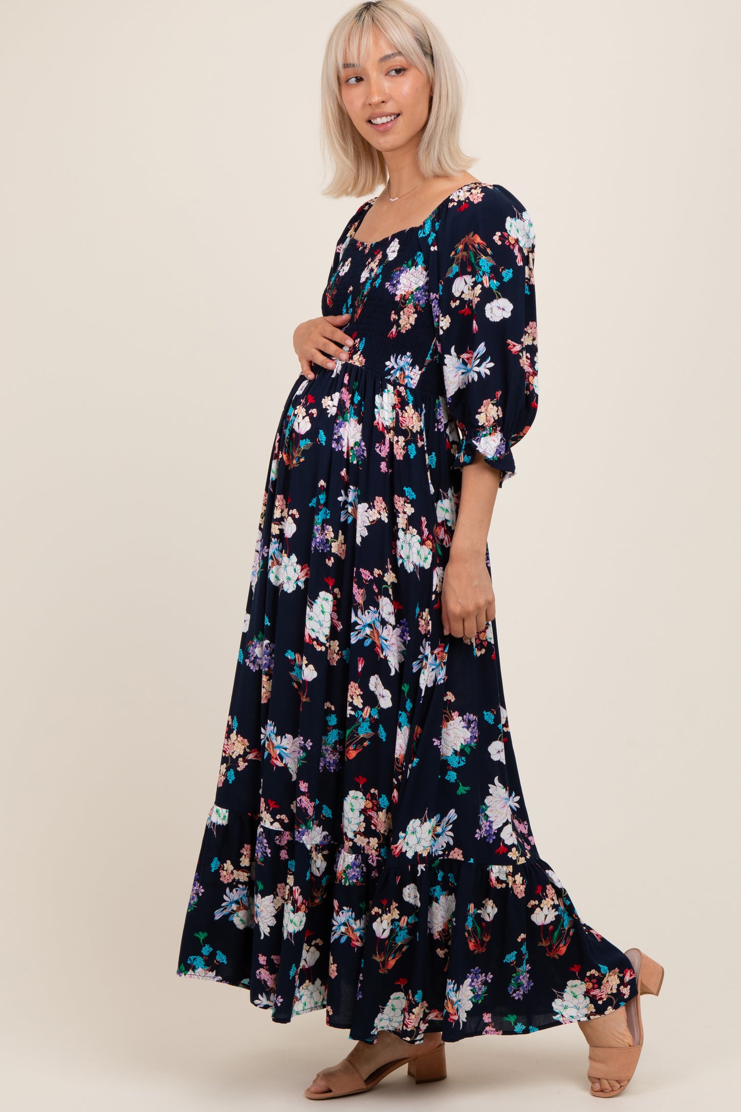 woman wearing a black floral print maternity maxi dress with puff sleeves and a visible baby bump