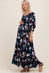 woman wearing a black floral print maternity maxi dress with puff sleeves and a visible baby bump