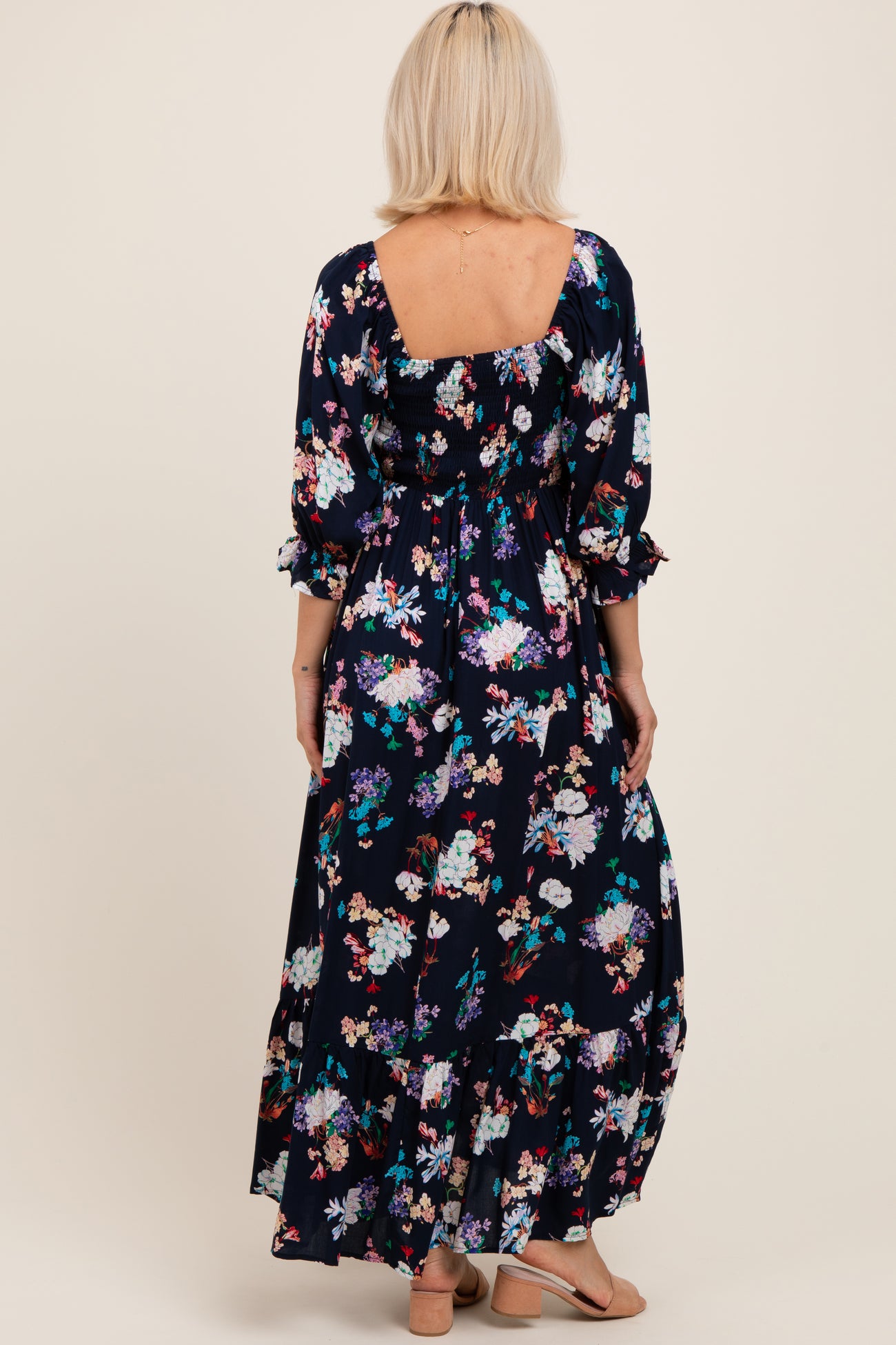 woman wearing a navy floral maxi maternity dress with three-quarter sleeves and a square back