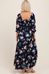 woman wearing a navy floral maxi maternity dress with three-quarter sleeves and a square back