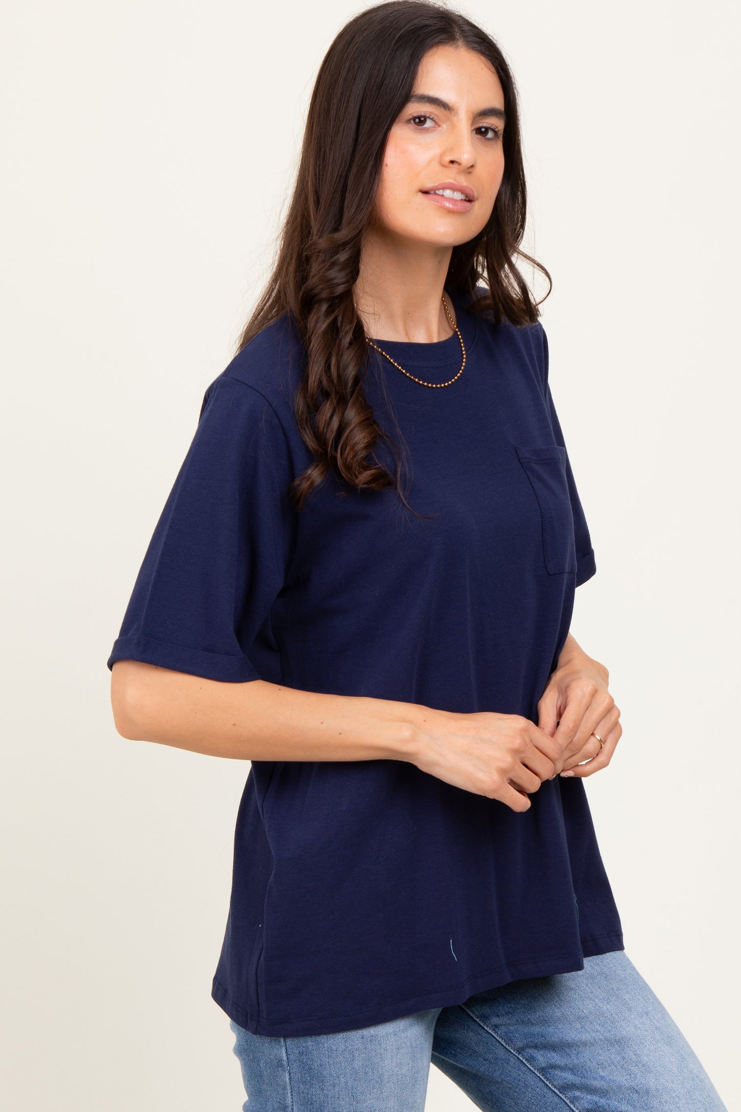 woman wearing a navy blue short sleeve t-shirt with a chest pocket and relaxed fit, styled with light blue jeans