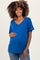 woman wearing a bright blue short sleeve maternity top and holding her baby bump