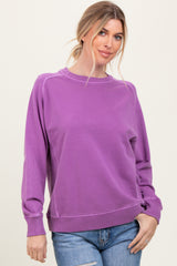 woman wearing a purple oversized sweatshirt with a crew neckline and ribbed cuffs, paired with blue jeans