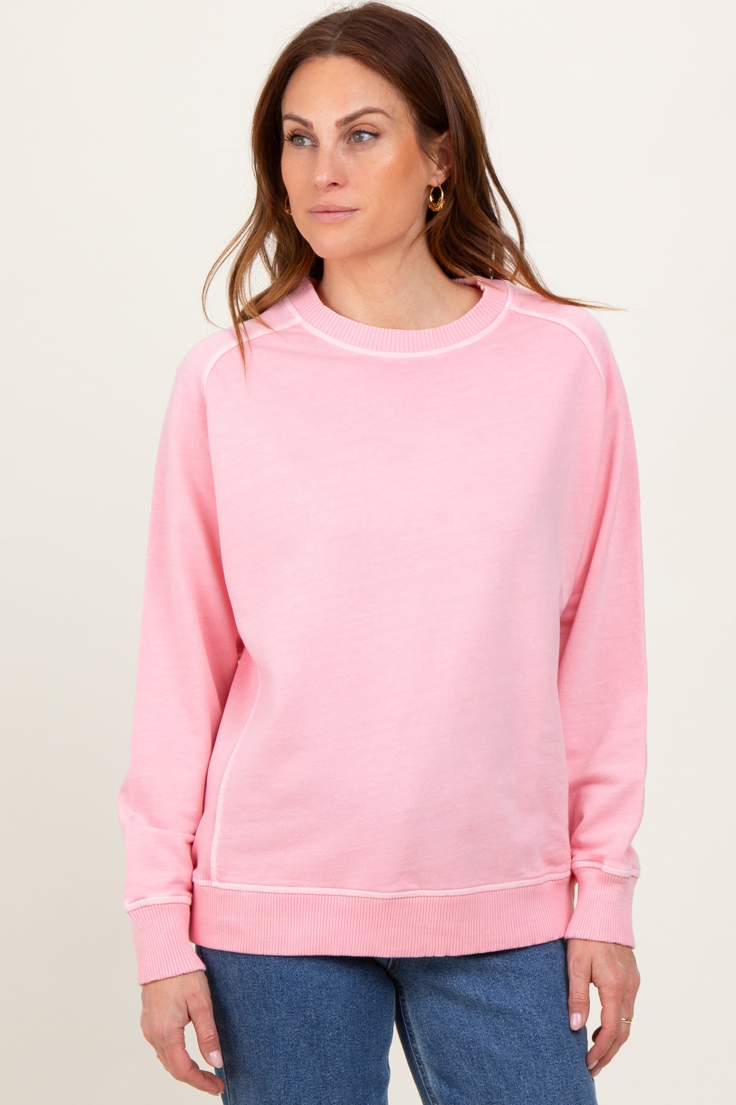 woman wearing a pink long sleeve sweatshirt with ribbed cuffs and a relaxed fit
