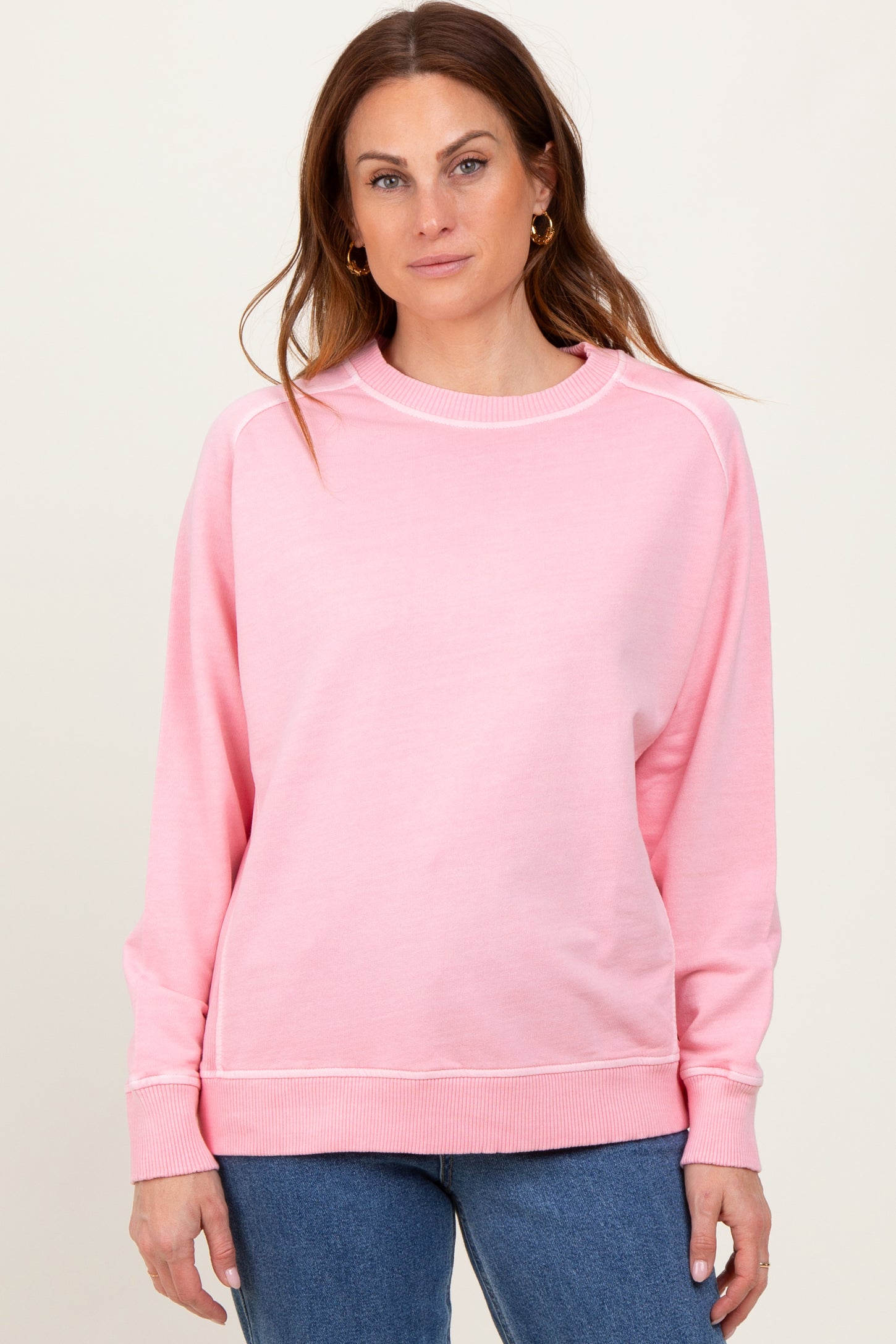 woman wearing a light pink long sleeve sweatshirt with a relaxed fit and ribbed cuffs