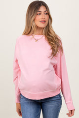 woman wearing a light pink maternity sweatshirt with a relaxed fit and visible baby bump