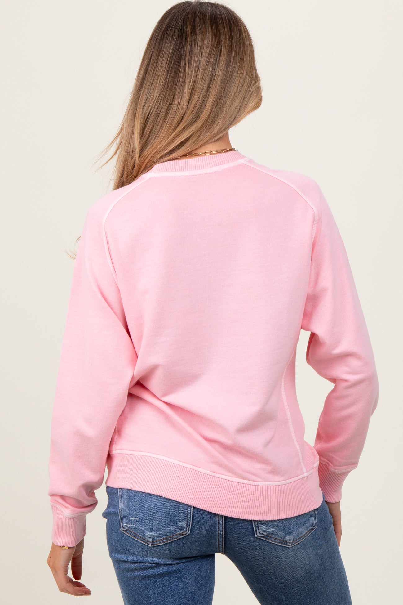woman wearing a light pink maternity sweatshirt with a relaxed fit, seen from the back