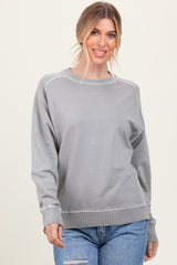 woman wearing a gray long sleeve sweatshirt with ribbed cuffs and hem, styled with distressed blue jeans