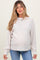 woman wearing a light beige maternity sweater with long sleeves and a relaxed fit, showing her baby bump