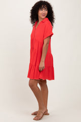 woman wearing a red short sleeve tiered dress with a collar and frayed hem, standing sideways