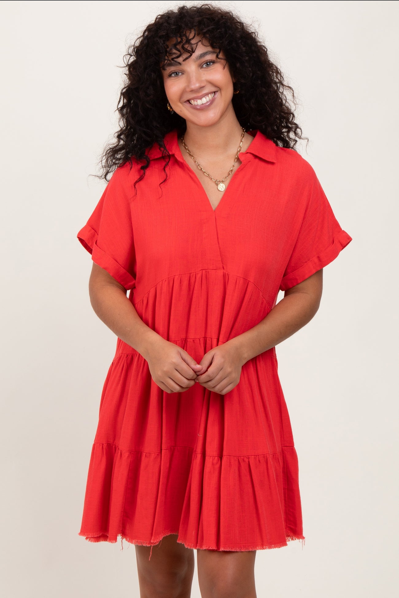 woman wearing a bright red short sleeve dress with a collared neckline and tiered ruffle hem
