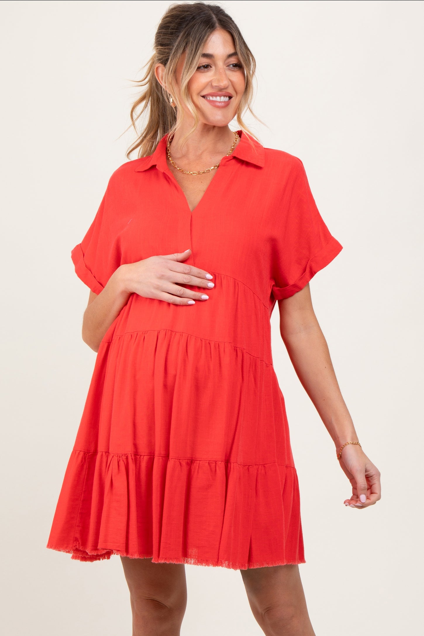woman wearing a red short sleeve maternity dress with a tiered design and a visible baby bump