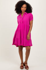 woman wearing a bright pink short sleeve tiered dress with a button-down collar and a flared silhouette