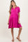 woman wearing a pink maternity dress with short sleeves and button details, standing and smiling