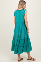 woman wearing a teal tiered maxi dress with ruffled sleeves and hem, styled with brown sandals