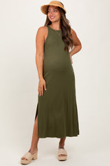 woman wearing an olive green maternity maxi dress with side slits and a straw hat, showing her baby bump