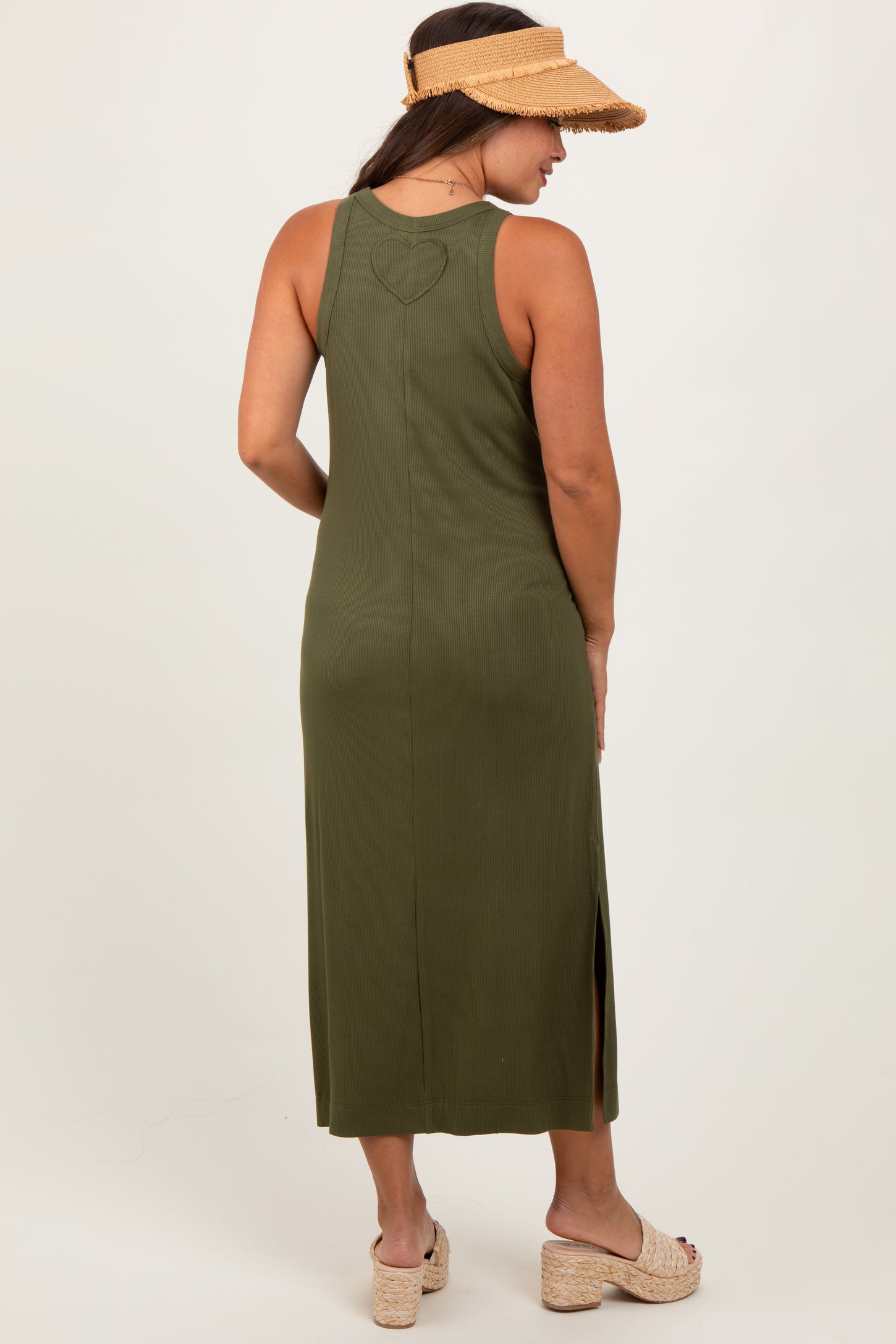 woman wearing a dark green maternity maxi dress with a heart detail on the back and side slits