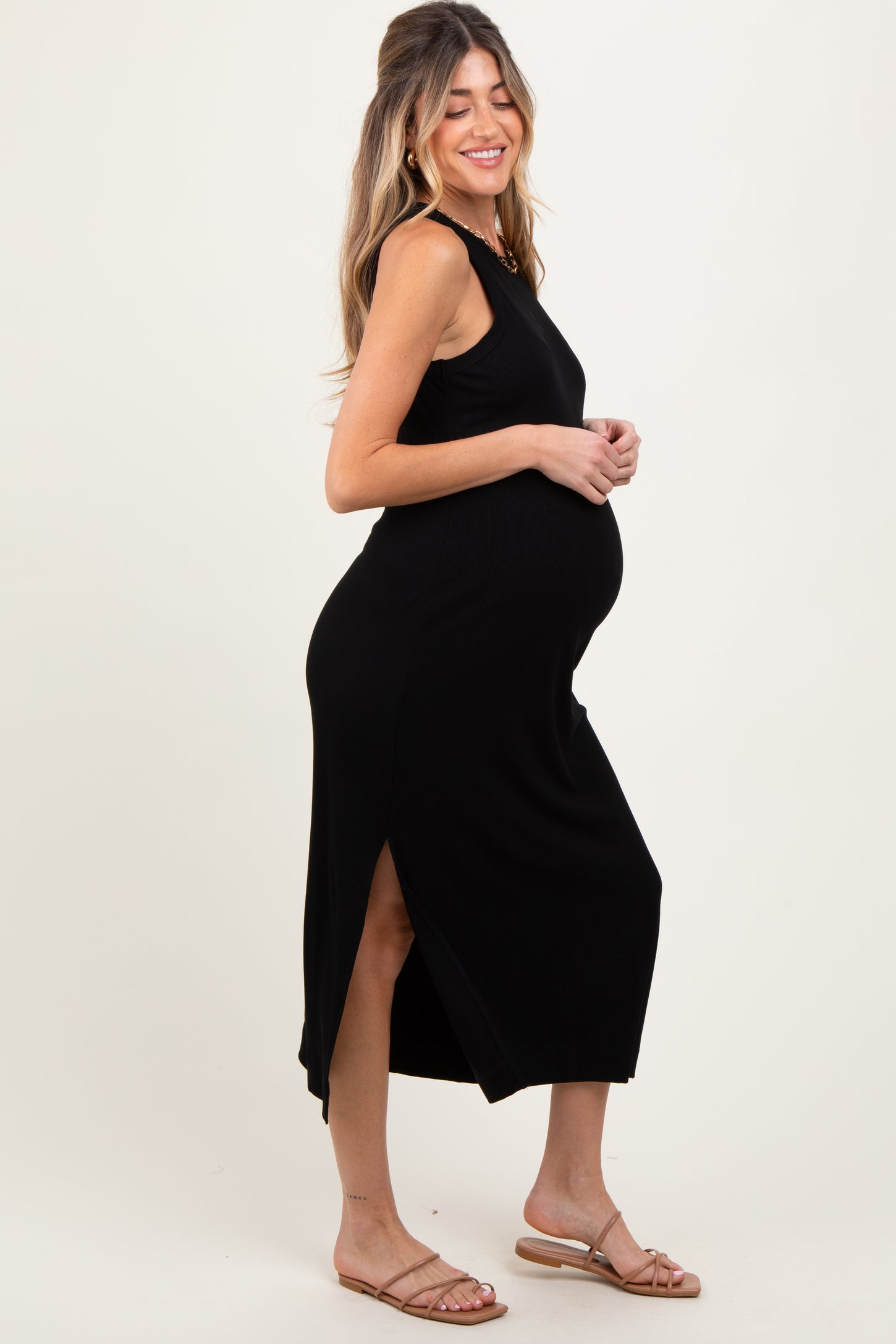 woman wearing a black sleeveless maternity dress with side slits and a visible baby bump
