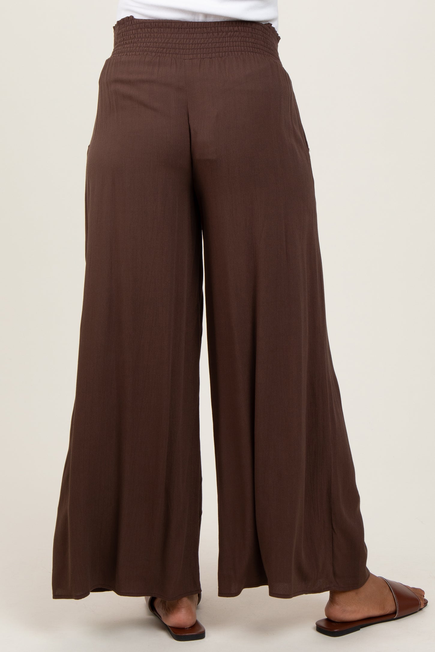 woman wearing brown maternity palazzo pants with a smocked waist from the back
