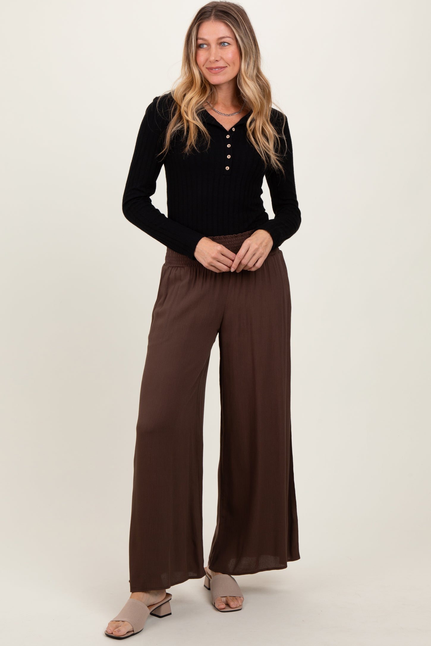 woman wearing a black ribbed long sleeve henley top and brown wide-leg pants
