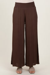 woman wearing brown wide-leg pants with a smocked waistband and side slits, styled with open-toe shoes