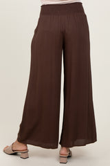 woman wearing brown wide-leg trousers with a smocked waistband, viewed from the back