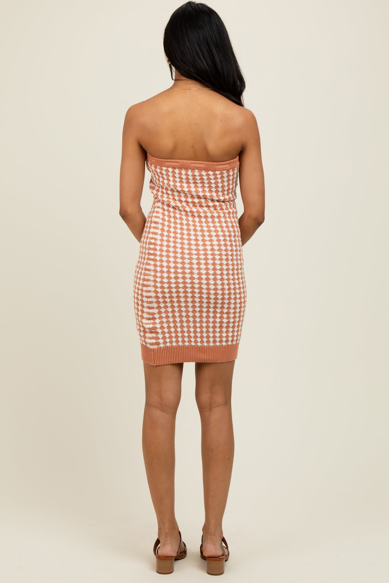 woman wearing a peach and white checkered strapless knit dress, showing the back view