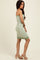 woman wearing a fitted green and white checkered strapless dress with a ribbed hem and simple heels