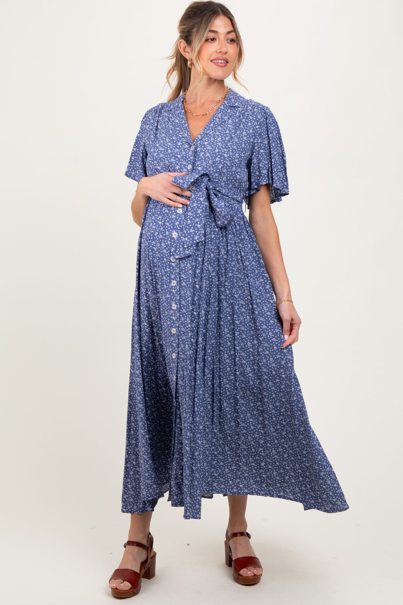 woman wearing a blue floral maternity wrap dress with short sleeves and a tie waist, showing her baby bump