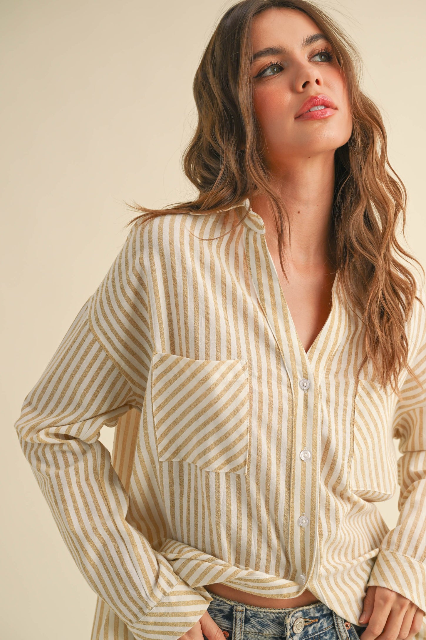 woman wearing a yellow and white striped long sleeve button-up shirt with a front pocket