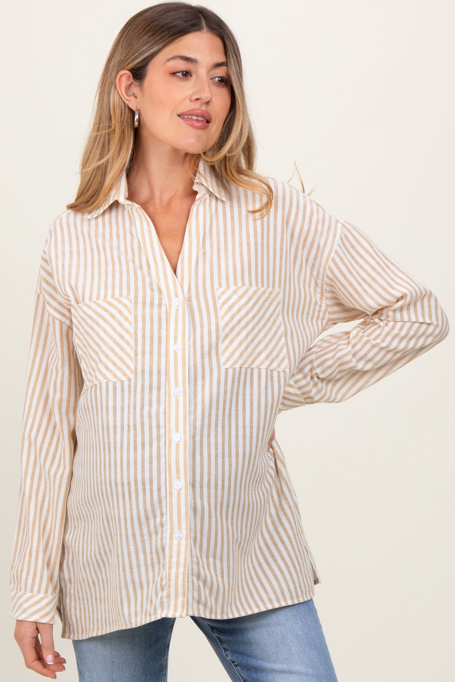 woman wearing a striped maternity shirt in beige and white, paired with blue jeans and showing a baby bump