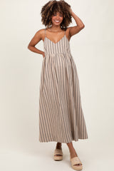 woman wearing a tan and navy striped maternity maxi dress with a flowy skirt and spaghetti straps, showing her baby bump