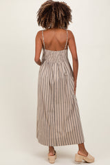 woman wearing a beige and navy striped backless maxi maternity dress with adjustable straps and smocked back detail