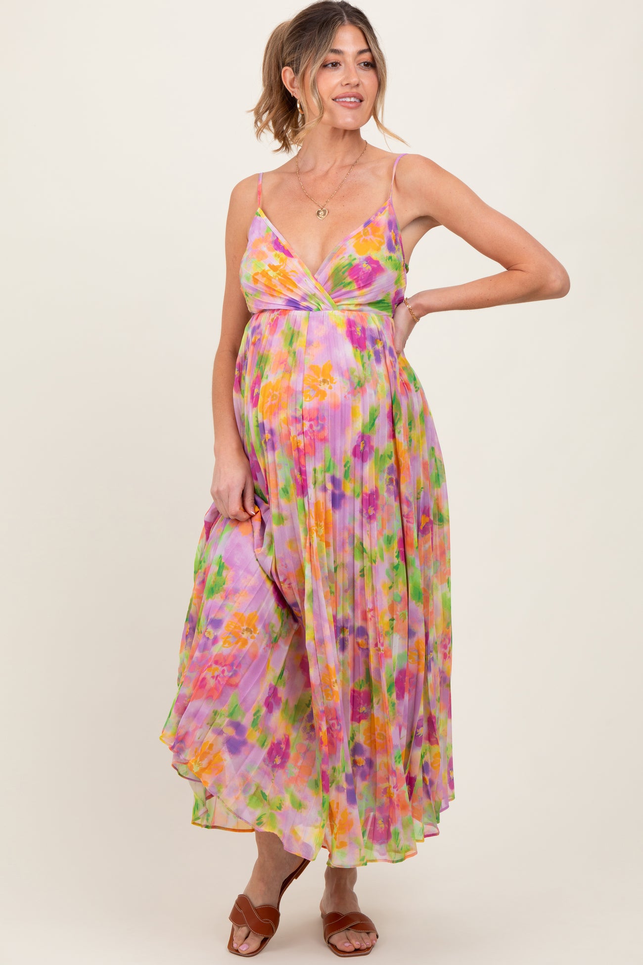 woman wearing a floral print maternity maxi dress with a v-neckline and a flowing skirt, showcasing her baby bump