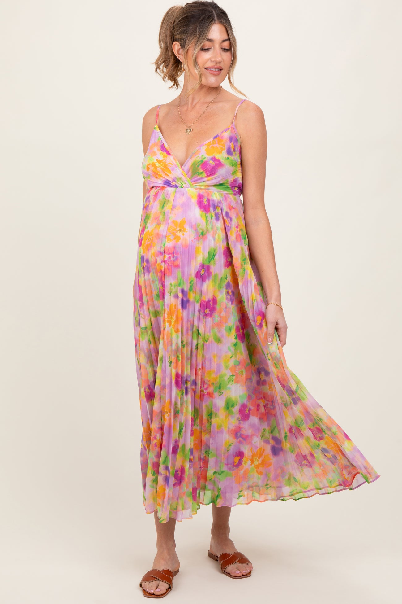 woman wearing a colorful floral maternity maxi dress with a pleated design and a visible baby bump