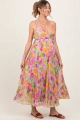 woman wearing a floral pleated maternity dress in pastel colors and showing her baby bump