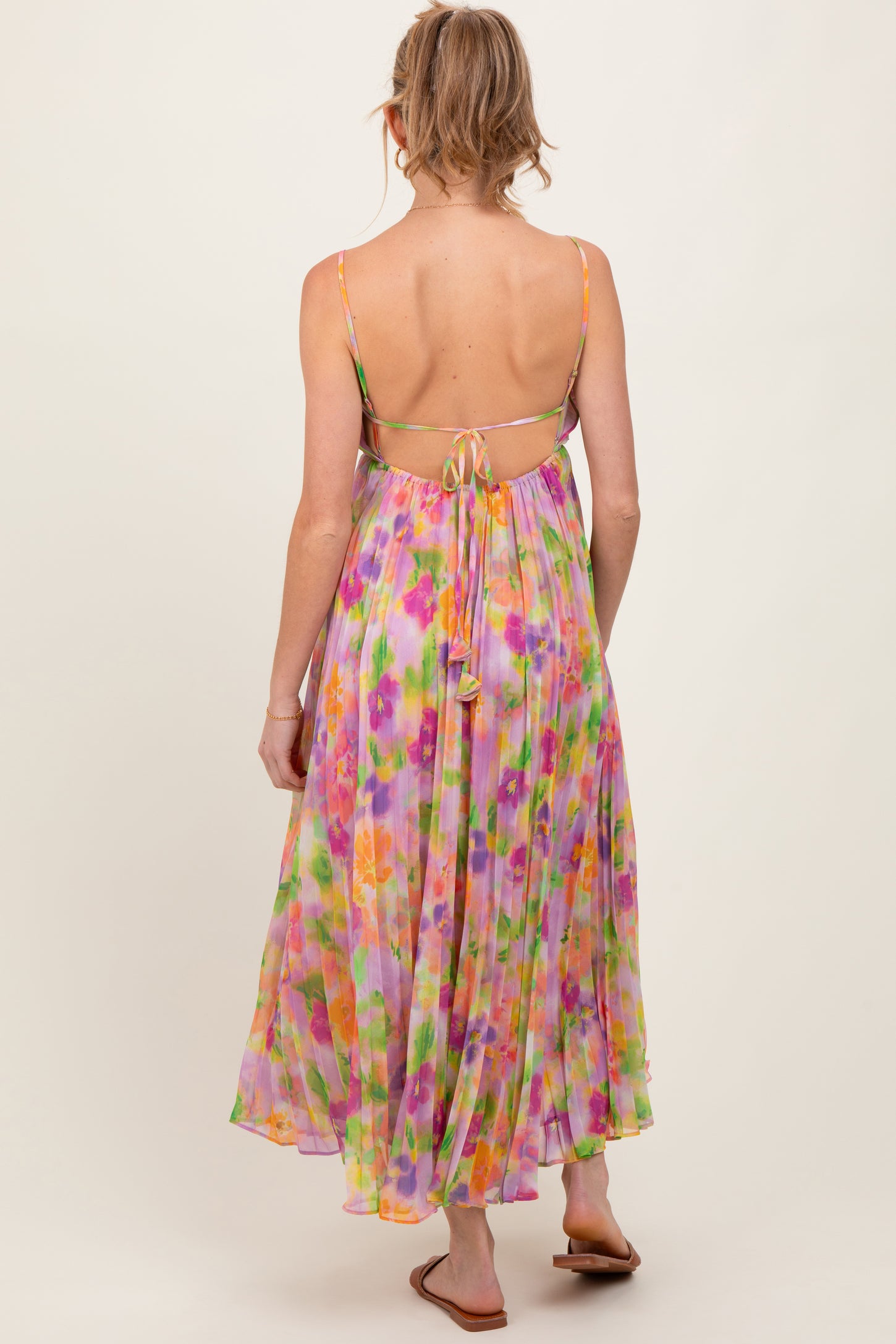 woman wearing a multi-colored floral maxi maternity dress with a tie-back detail and a flowing silhouette