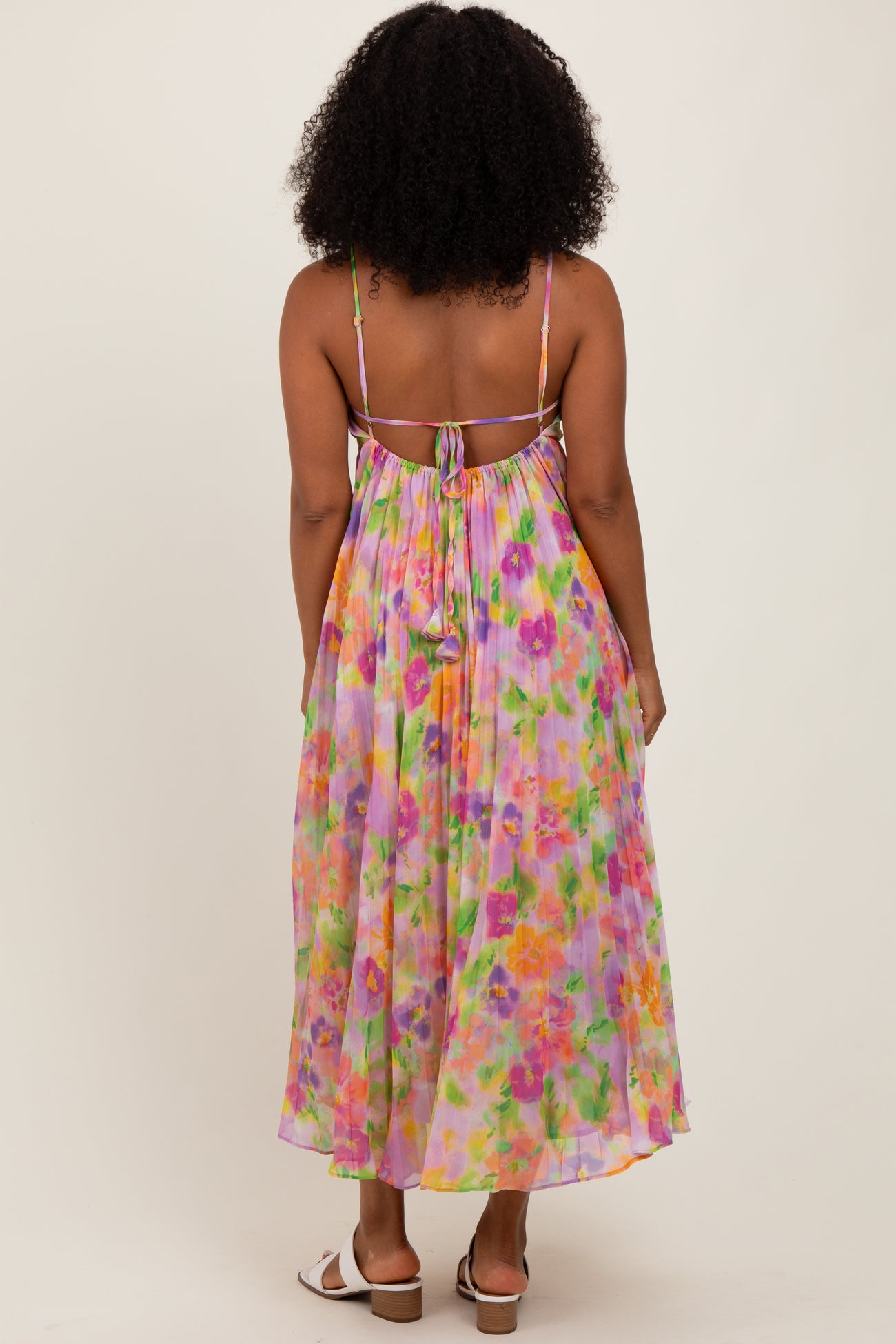 woman wearing a colorful floral maxi dress with a tied back and spaghetti straps