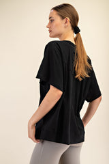 woman wearing a relaxed fit black t-shirt with wide sleeves, styled with gray leggings and hair tied back in a ponytail