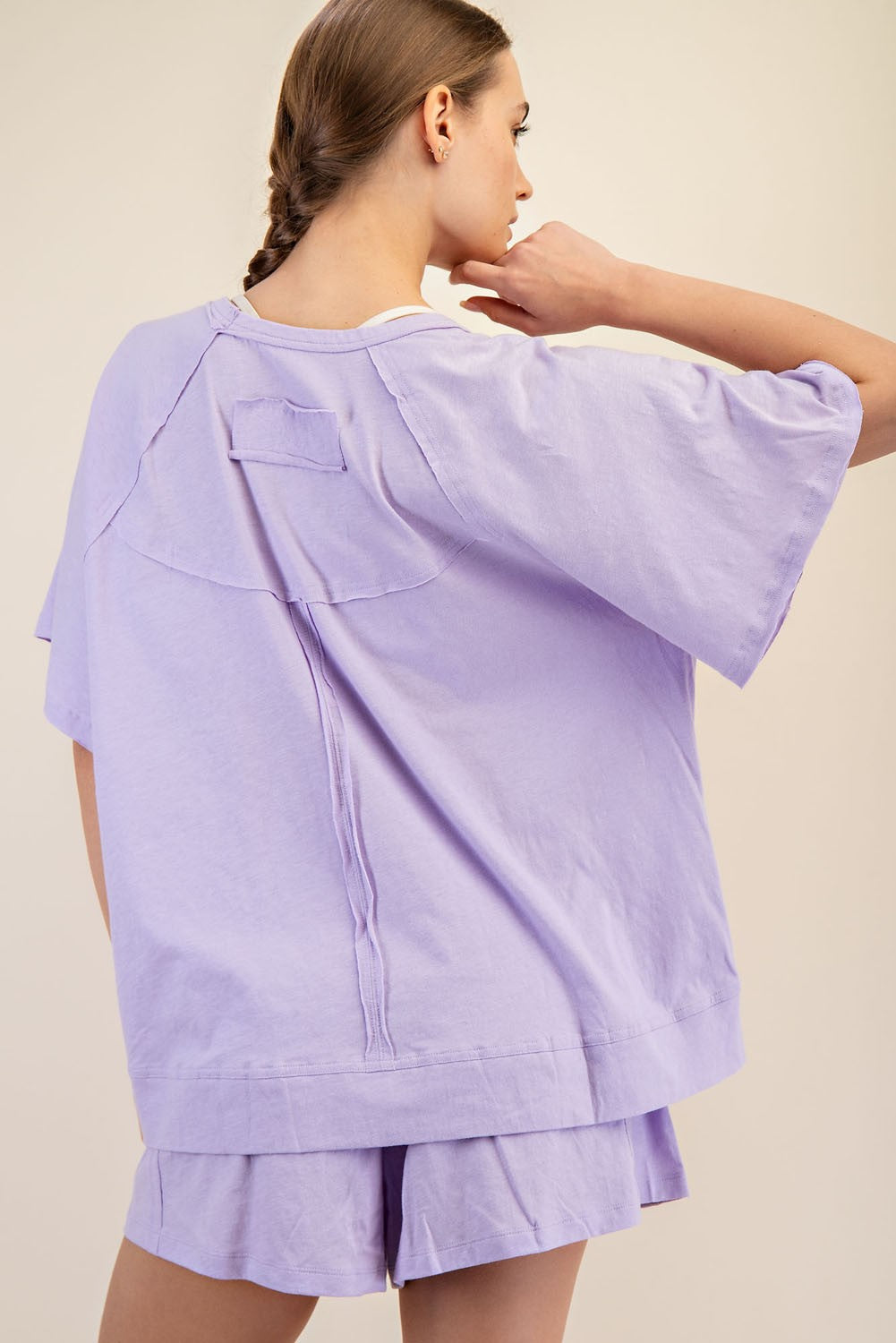 woman wearing a lavender oversized short sleeve top and matching shorts, showing the back details of the outfit