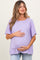 woman wearing a light purple maternity top and holding her baby bump