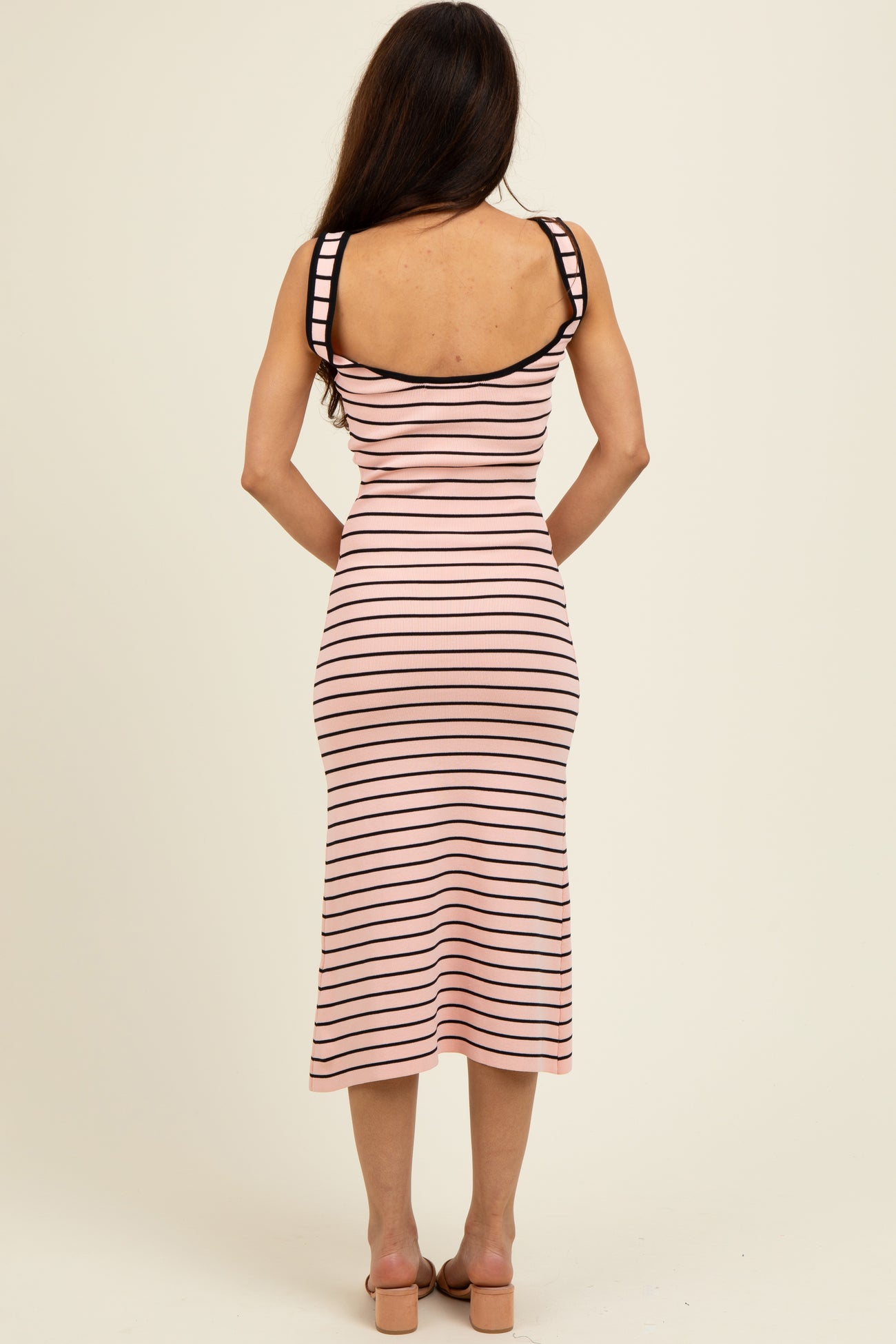 woman wearing a fitted pink and black striped midi dress with spaghetti straps and a scoop back