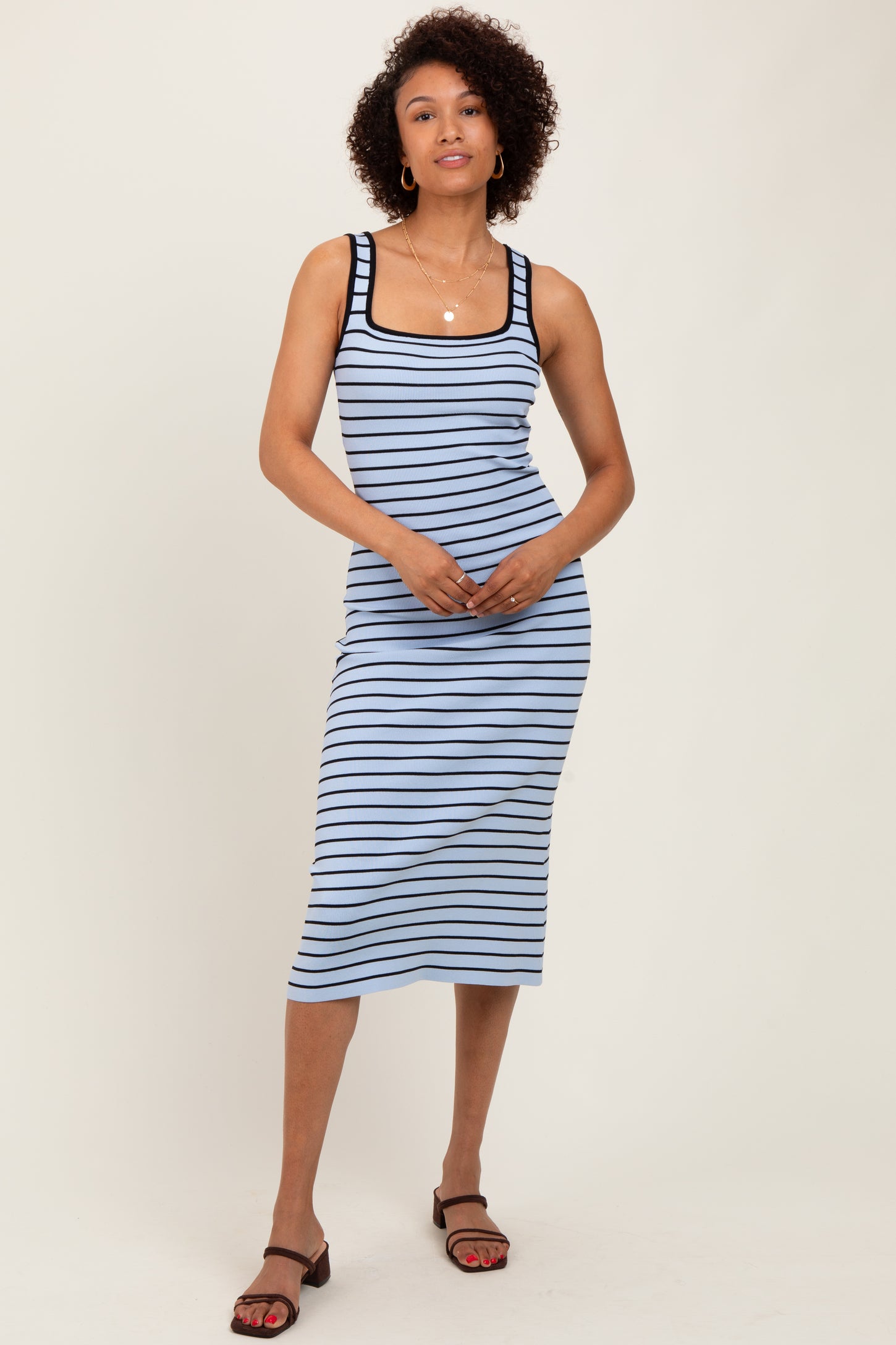 woman wearing a light blue striped midi dress with black trim and spaghetti straps