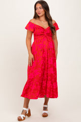 woman wearing a hot pink floral off-shoulder maternity dress with a smocked bodice and ruffle hem, showing her baby bump