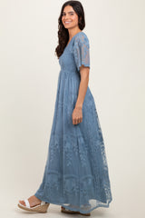 woman wearing a blue embroidered maxi dress with short sleeves and a fitted bodice