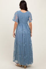 woman wearing a light blue maxi dress with embroidered details and short sheer sleeves, shown from the back