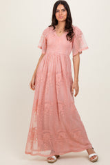 woman wearing a pink maxi dress with floral embroidery and short flutter sleeves
