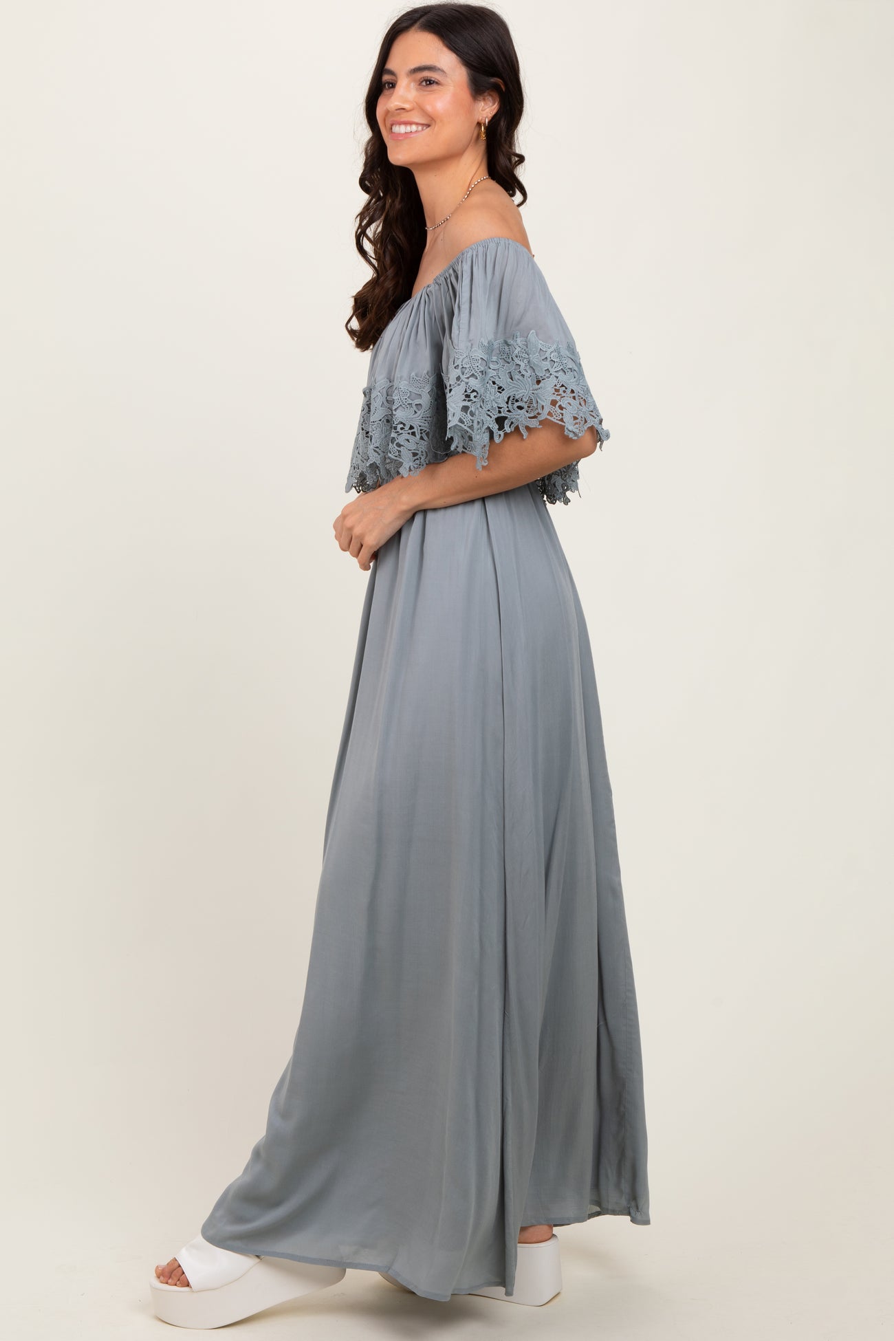 woman wearing a long gray off-shoulder maxi dress with lace details and flowing silhouette