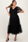woman wearing a black maternity dress with puff sleeves and tulle detailing, showing her baby bump