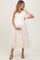 woman wearing a cream maternity dress with short puff sleeves and tiered tulle skirt, cradling her baby bump